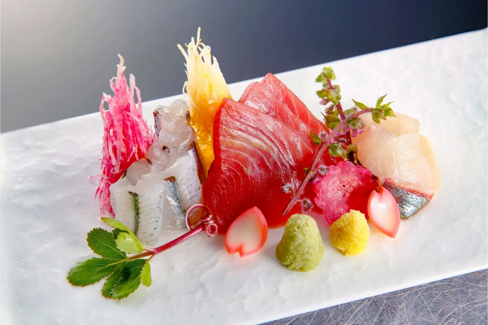 Elegantly plated fresh sashimi with garnishes, wasabi and decorative greens