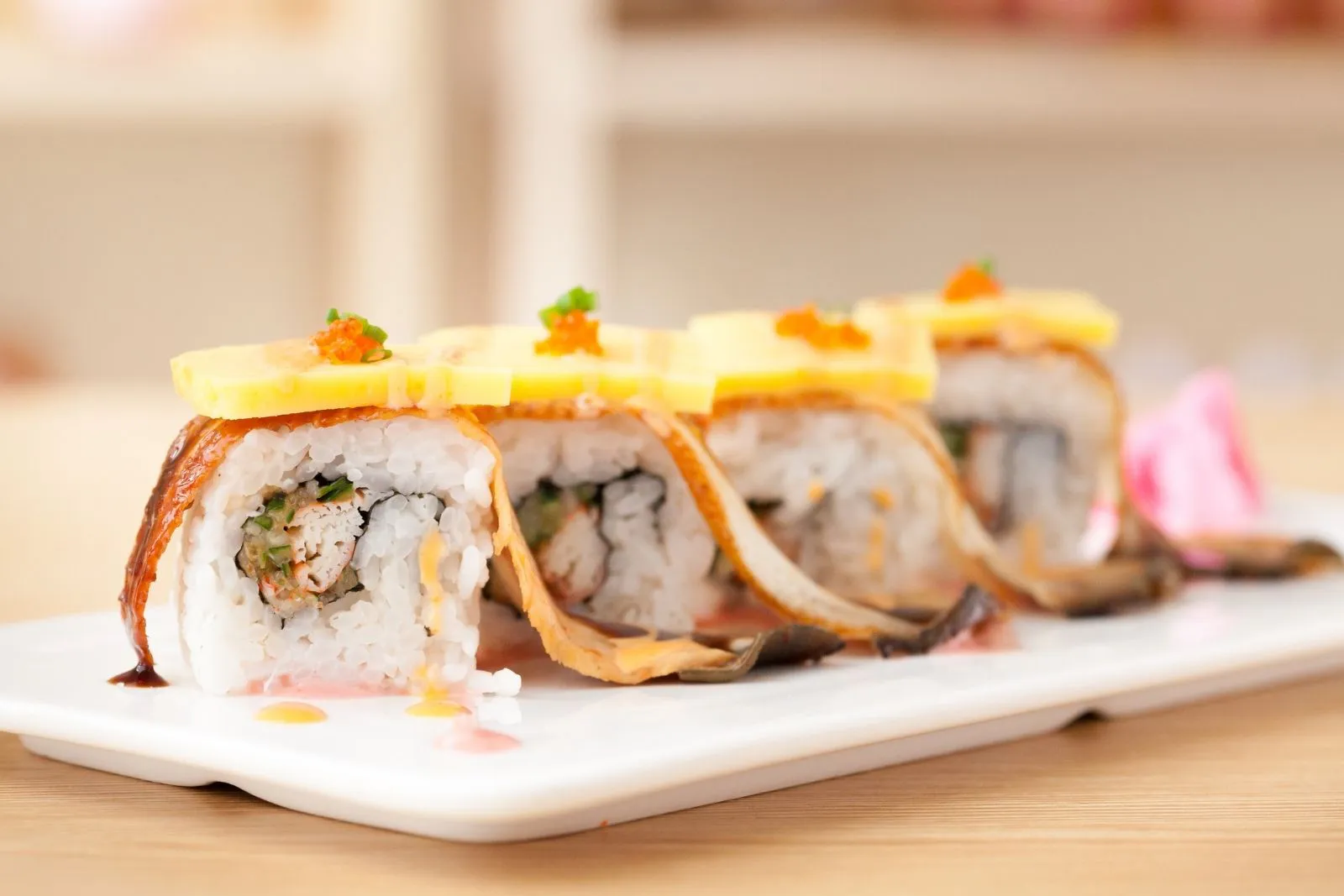 Special sushi roll topped with mango slices, eel and bright orange fish roe